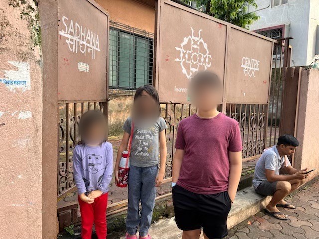 Three children, faces blurred, outside the gate of the Learner’s Collective in Mumbai
