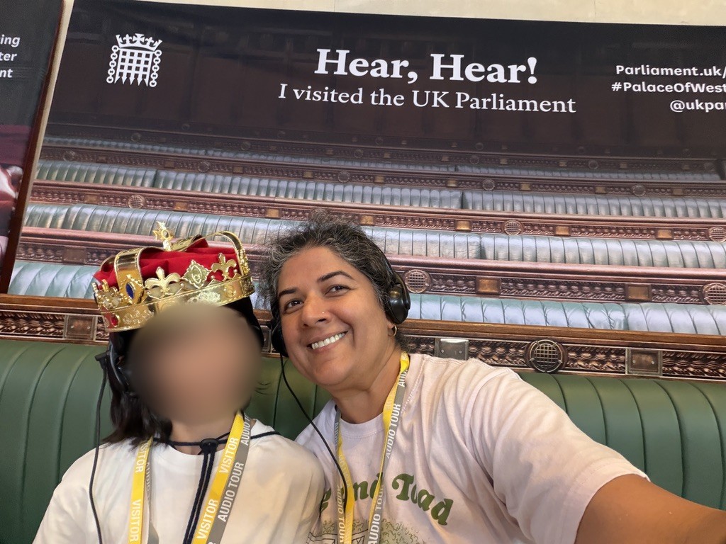 Nandini Deo and her child, face blurred, in a crown at the UK Parliament
