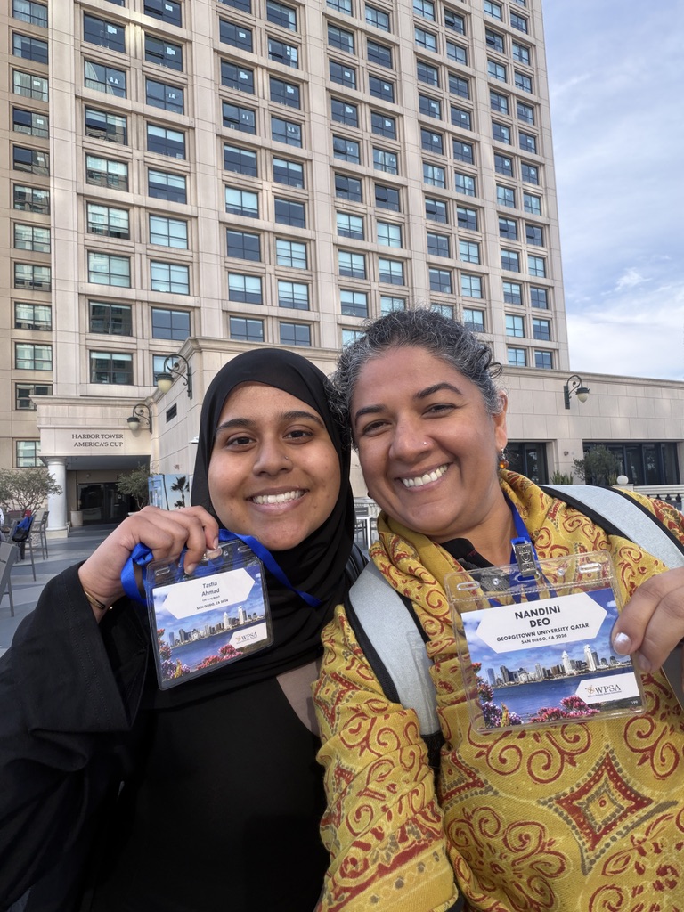 Nandini Deo and Tasfia Ahmad holding their WPSA conference badges in San Diego